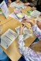 Schülerinnen und Schüler beim Experiment mit Joghurt und Löffeln am Tisch.