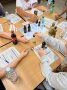 Menschen beim Verkosten von Zuckerlösungen mit Pipettem und Löffeln am Tisch